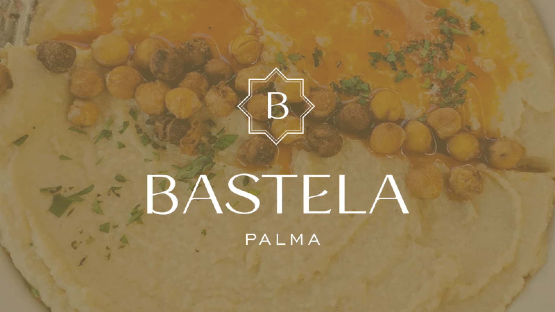 Logotipo Bastela Palma sobre plato de hummus marroquí